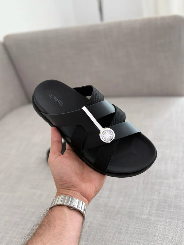 Hermès Kazimir sandal, crafted from black leather and fabric straps featuring an interlaced "H" silhouette.